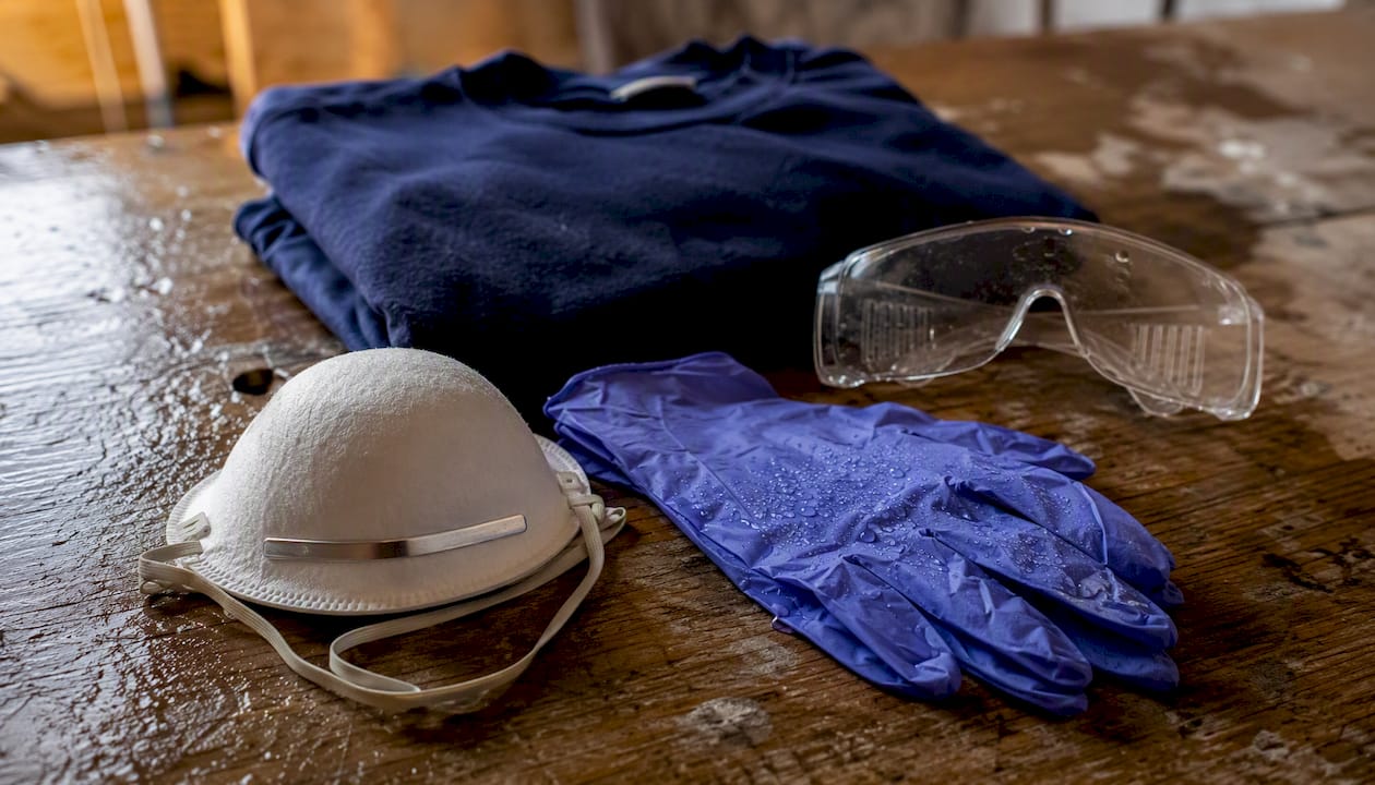 N95 mask gloves goggles and coveralls on workbench
