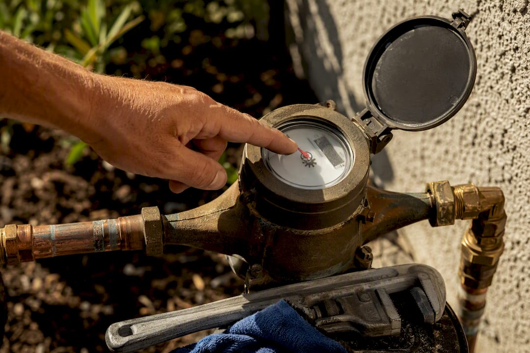 Hand checking a moving water meter indicator