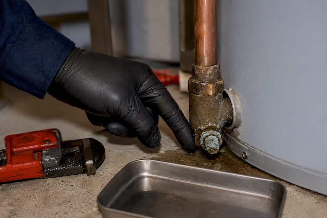 Technician inspecting corroded heater drain fitting